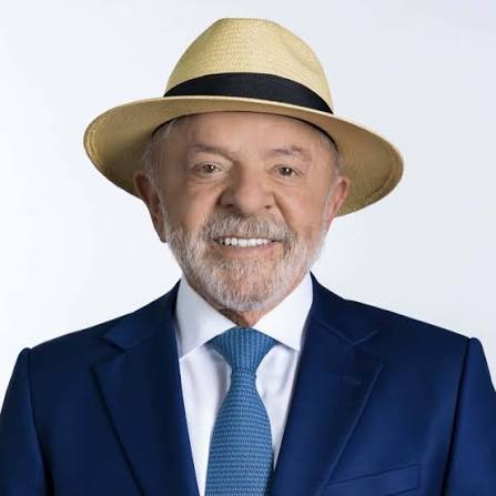 Presidente Lula sorrindo, de chapéu e terno azul